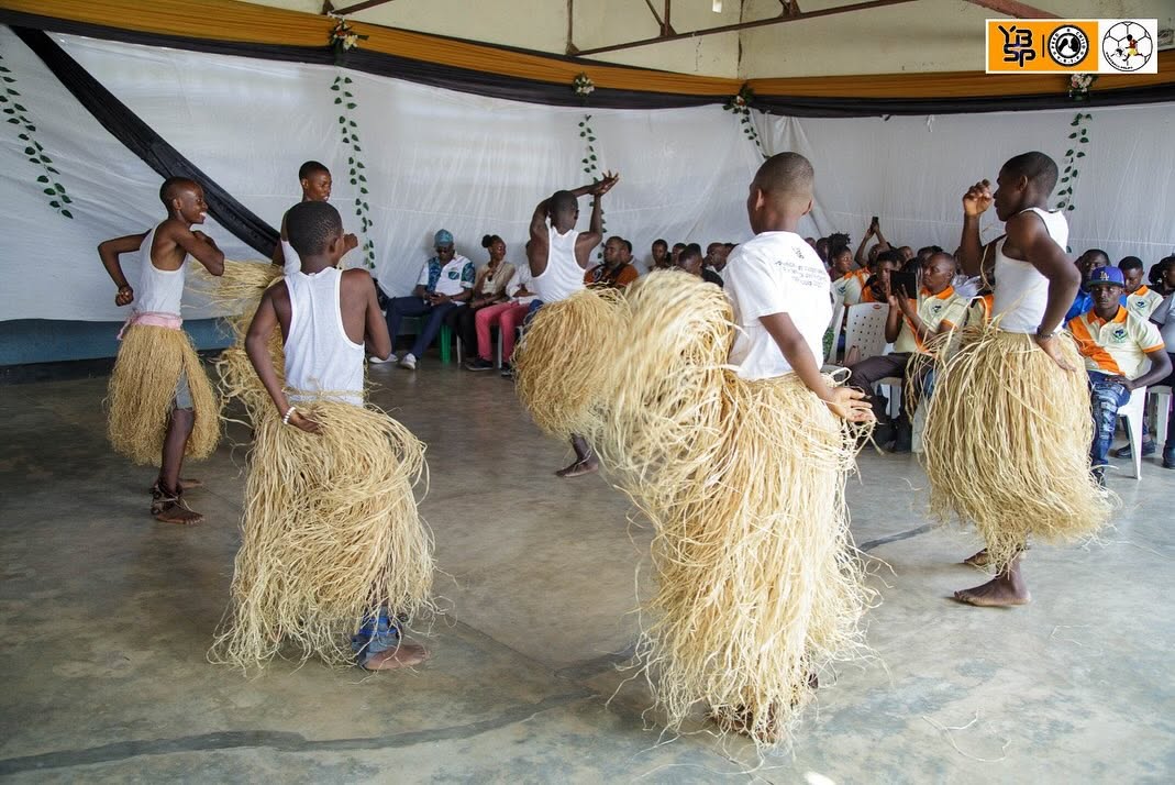 Young Burundian dancers in traditional straw costumes performing for an audience