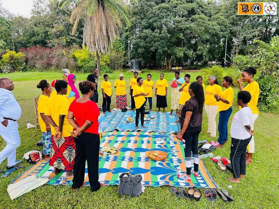 Community members in matching yellow shirts standing in a circle at an outdoor gathering