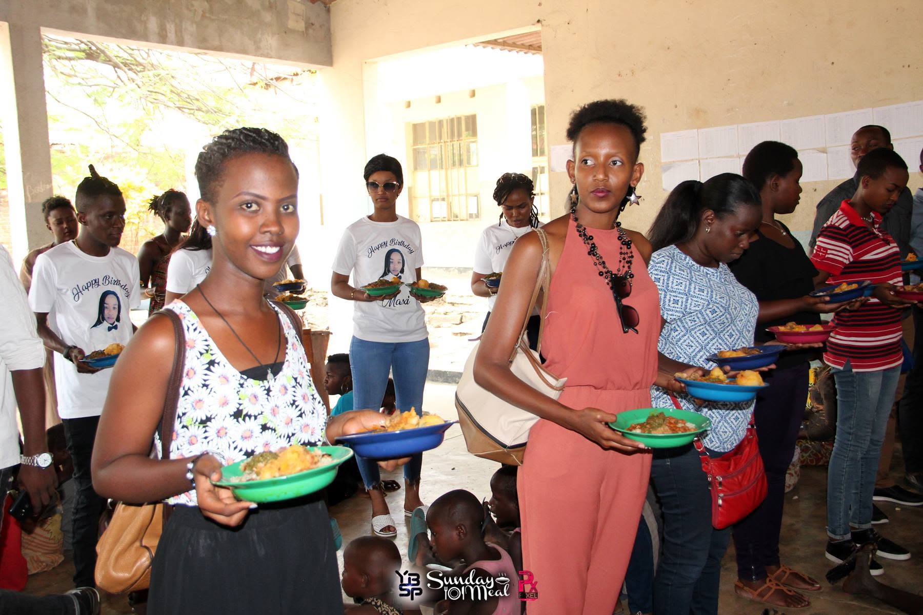 Volunteers serving plates of food to children at a YBSP Sunday Meal distribution
