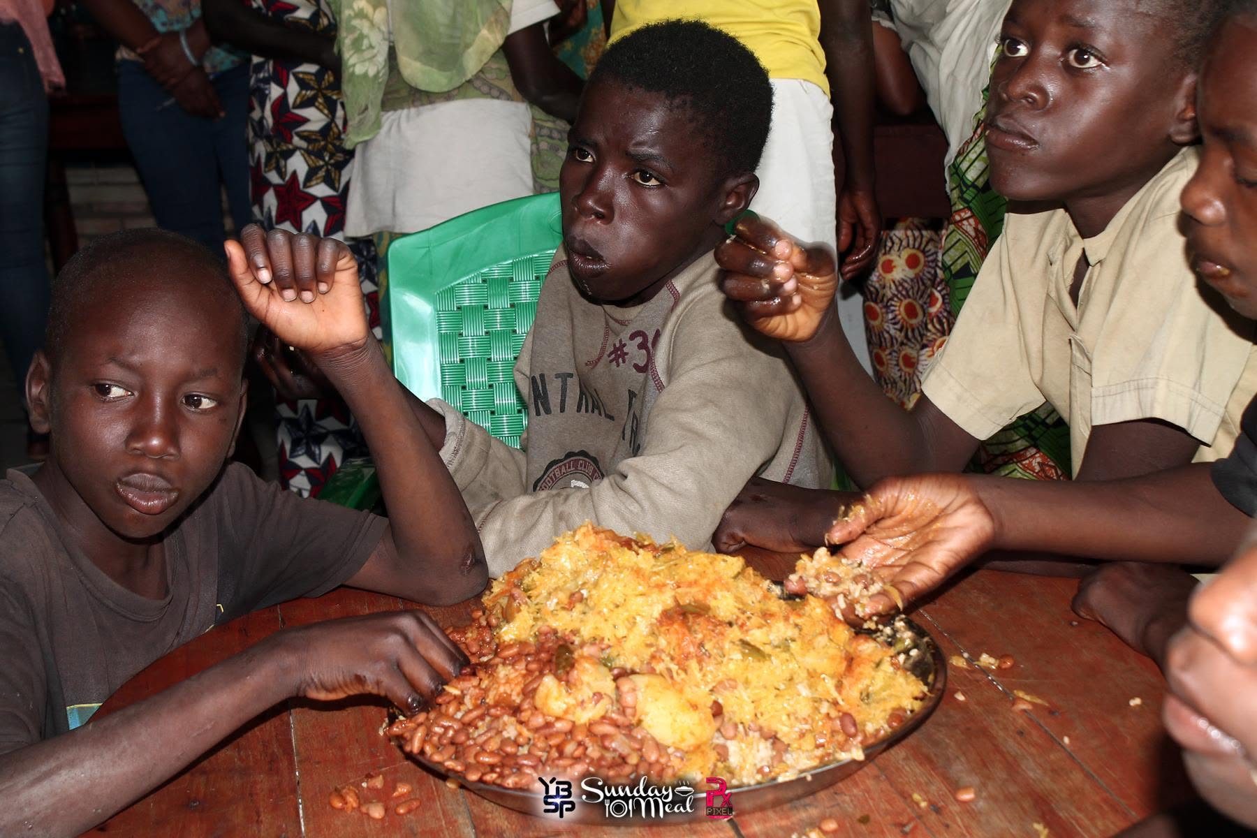 Burundian children sharing a large communal platter of rice and beans