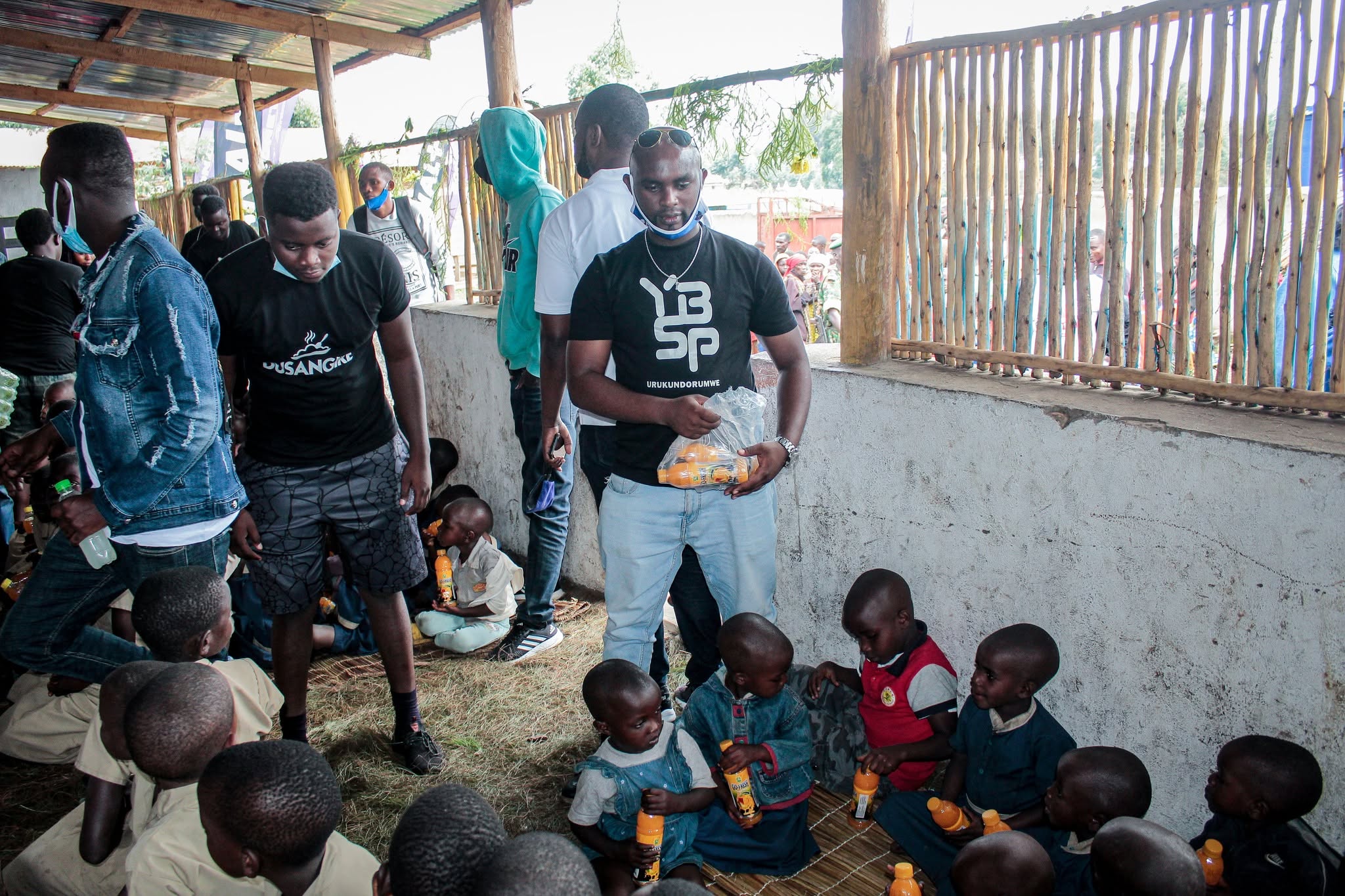 A YBSP volunteer distributing bottled drinks to seated children during a community outreach
