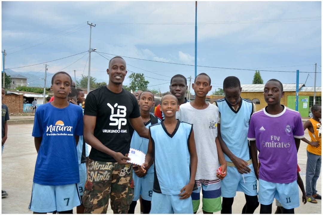 A YBSP volunteer posing with a youth basketball team outdoors